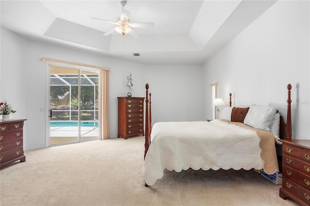 bedroom with access to outside, light colored carpet, a ceiling fan, a tray ceiling, and visible vents