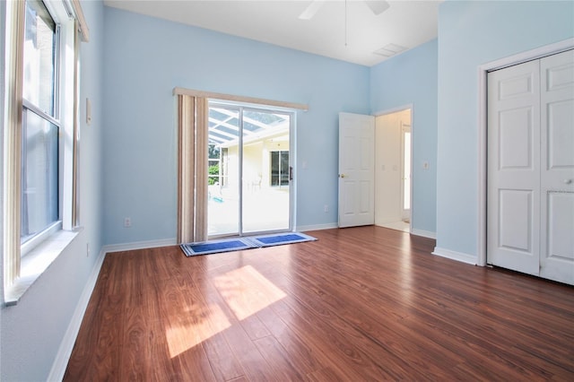 unfurnished bedroom with access to outside, a ceiling fan, baseboards, and dark wood-style floors