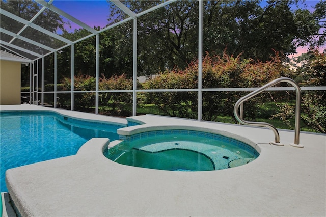view of swimming pool featuring a lanai, a pool with connected hot tub, and a patio area