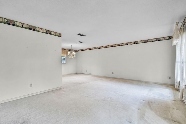 spare room with visible vents, light colored carpet, and a notable chandelier