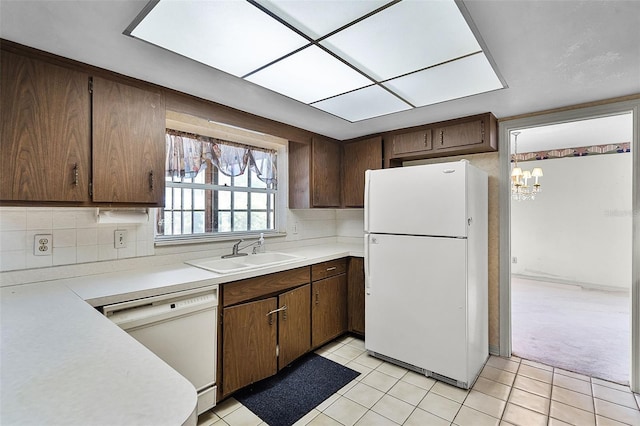 kitchen featuring an inviting chandelier, a sink, white appliances, light countertops, and light tile patterned floors