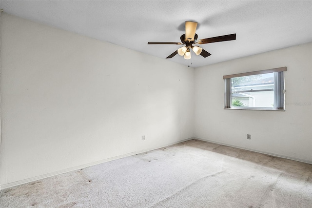 carpeted spare room with baseboards and a ceiling fan