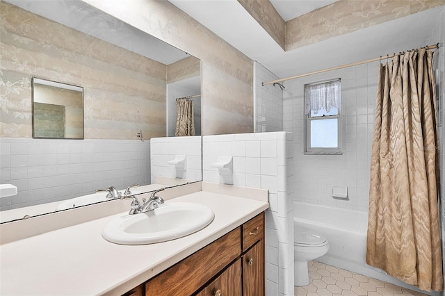 bathroom featuring vanity, toilet, tile patterned floors, shower / bathtub combination with curtain, and tile walls