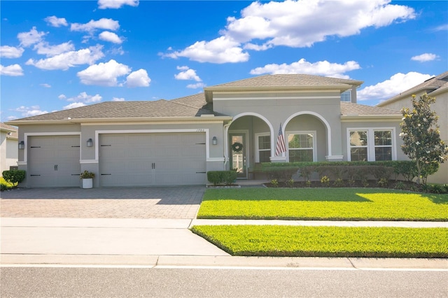 mediterranean / spanish home with an attached garage, stucco siding, driveway, and a front lawn