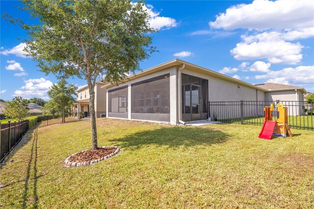 back of house featuring a lawn, a sunroom, and a fenced backyard