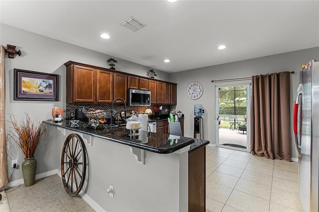 913 Bending Oak Trl, Winter Garden, FL 34787 - kitchen featuring appliances with stainless steel finishes, a peninsula, tasteful backsplash, a breakfast bar area, and light tile patterned floors