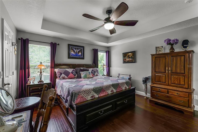 913 Bending Oak Trl, Winter Garden, FL 34787 - bedroom featuring a tray ceiling, dark wood-type flooring, baseboards, a ceiling fan, and a textured ceiling