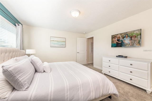 bedroom with baseboards and light carpet