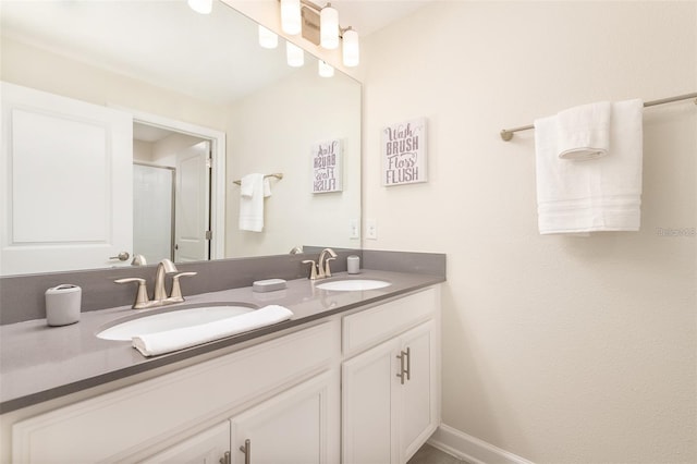 full bathroom featuring double vanity, a shower stall, and a sink