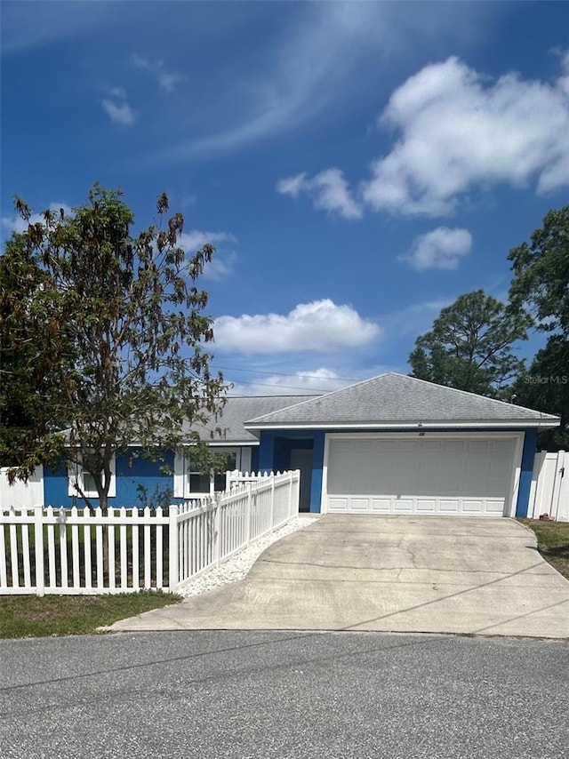 view of front of home featuring a garage, a fenced front yard, concrete driveway, and stucco siding