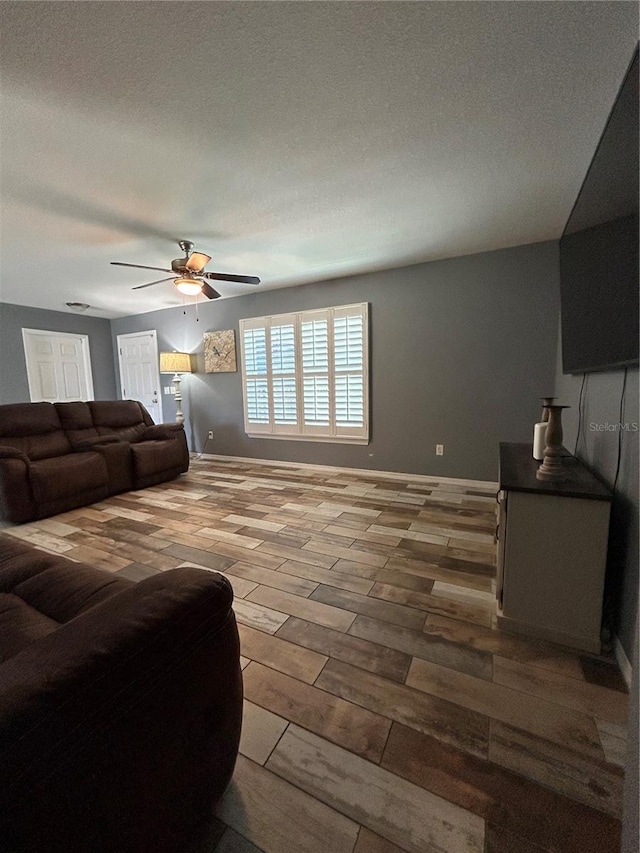 living room featuring a textured ceiling, ceiling fan, and wood finished floors