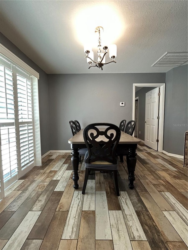 dining area with baseboards, wood-type flooring, and a chandelier
