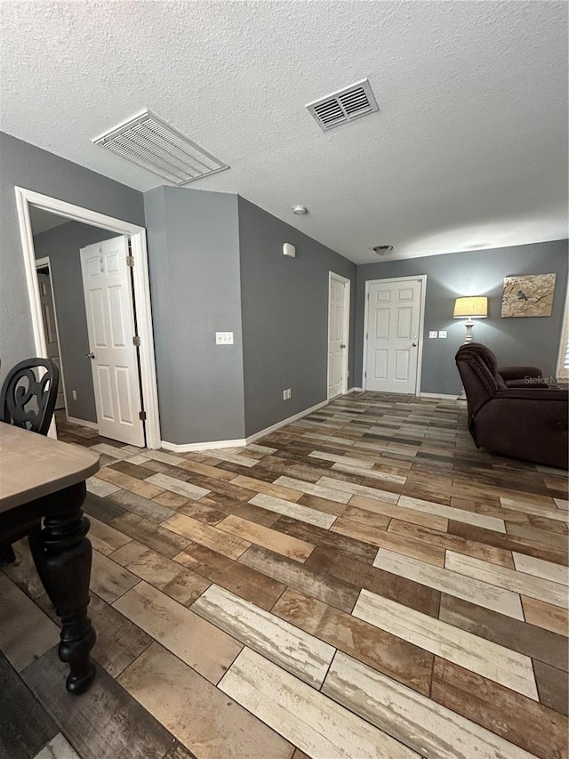 interior space featuring visible vents, a textured ceiling, and wood finished floors