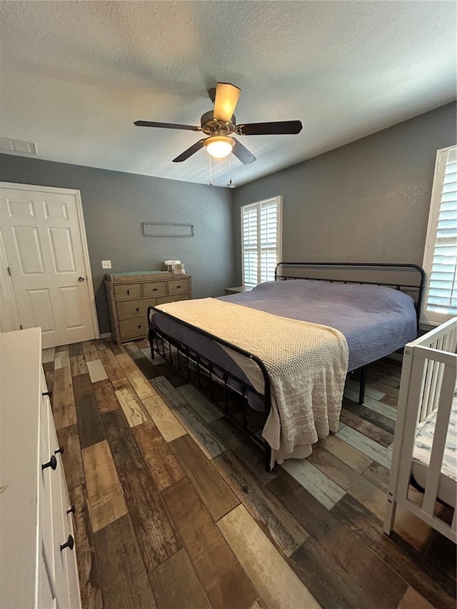 bedroom with wood-type flooring, a textured ceiling, and ceiling fan