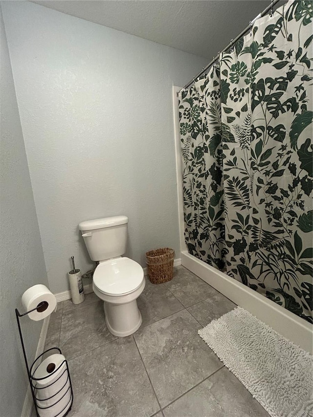 bathroom featuring baseboards, toilet, and a shower with curtain