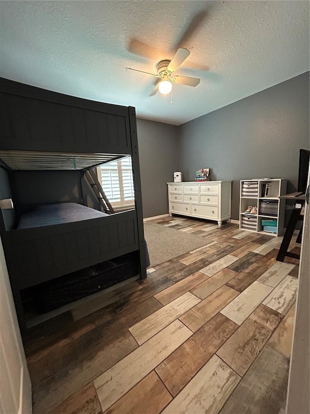 bedroom with wood-type flooring, a ceiling fan, a textured ceiling, and baseboards