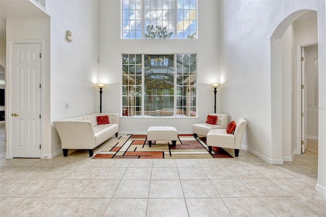 14003 Hampshire Bay Cir, Winter Garden, FL 34787 - living room featuring tile patterned flooring, arched walkways, baseboards, and a towering ceiling