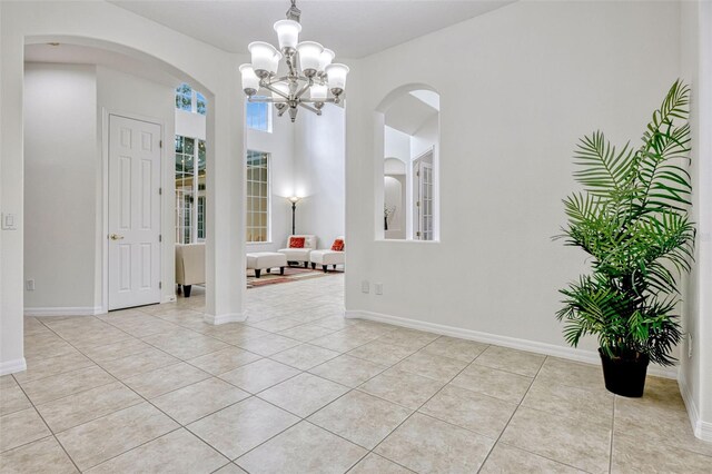 14003 Hampshire Bay Cir, Winter Garden, FL 34787 - empty room featuring light tile patterned flooring, arched walkways, an inviting chandelier, and baseboards
