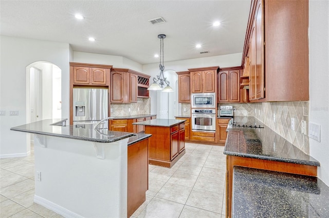 14003 Hampshire Bay Cir, Winter Garden, FL 34787 - kitchen featuring a kitchen island, visible vents, appliances with stainless steel finishes, arched walkways, and light tile patterned floors