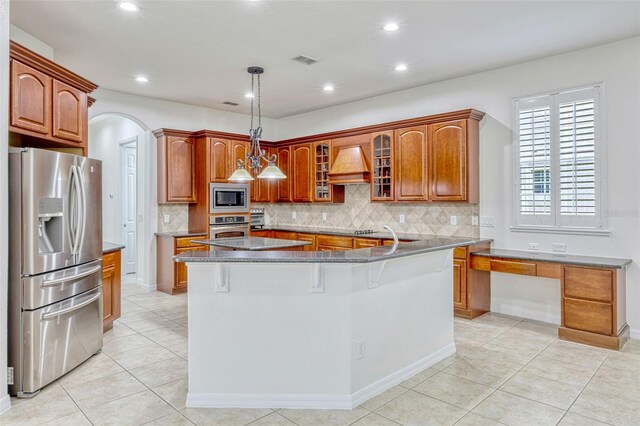 14003 Hampshire Bay Cir, Winter Garden, FL 34787 - kitchen with decorative backsplash, glass insert cabinets, custom range hood, light tile patterned floors, and stainless steel appliances
