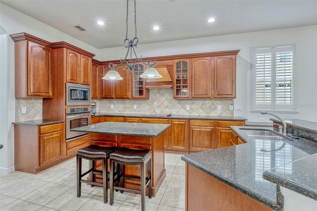 14003 Hampshire Bay Cir, Winter Garden, FL 34787 - kitchen featuring brown cabinetry, glass insert cabinets, a center island, a sink, and appliances with stainless steel finishes