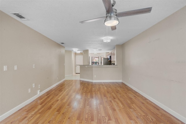 7449 Sugar Bend Dr Unit 7449, Orlando, FL 32819 - unfurnished living room featuring light wood-style flooring, a textured ceiling, baseboards, and a ceiling fan