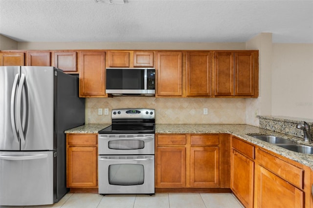 7449 Sugar Bend Dr Unit 7449, Orlando, FL 32819 - kitchen with appliances with stainless steel finishes, a sink, brown cabinetry, light stone countertops, and a textured ceiling