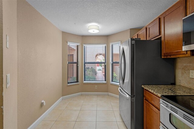 7449 Sugar Bend Dr Unit 7449, Orlando, FL 32819 - kitchen with appliances with stainless steel finishes, brown cabinets, decorative backsplash, light stone countertops, and baseboards