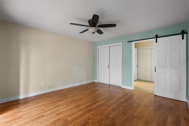7449 Sugar Bend Dr Unit 7449, Orlando, FL 32819 - unfurnished bedroom with a barn door, wood finished floors, baseboards, a closet, and a textured ceiling