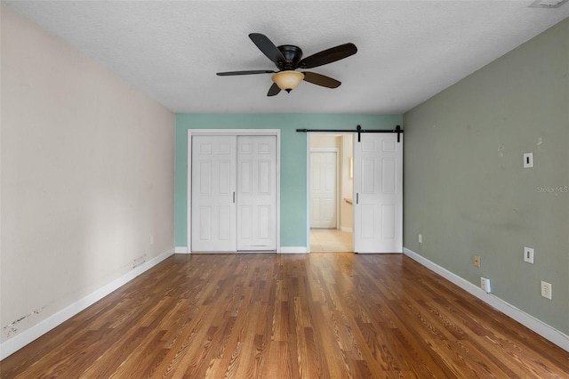 7449 Sugar Bend Dr Unit 7449, Orlando, FL 32819 - unfurnished bedroom featuring a barn door, wood finished floors, baseboards, a closet, and a textured ceiling