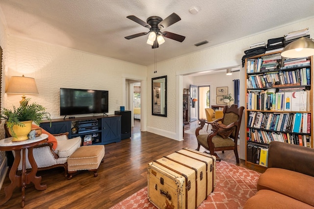living area featuring a textured ceiling, ceiling fan, visible vents, wood finished floors, and a textured wall