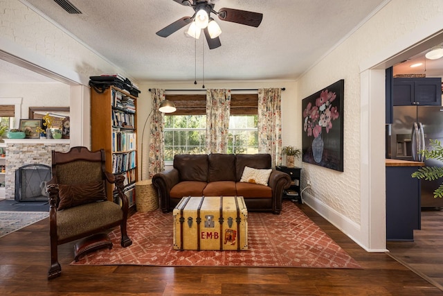living area with a textured ceiling, a textured wall, baseboards, and wood finished floors