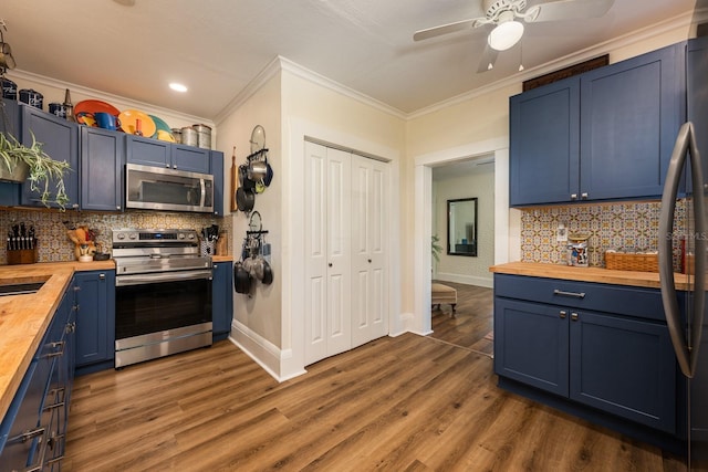kitchen featuring wood counters, stainless steel appliances, dark wood-type flooring, blue cabinetry, and ornamental molding