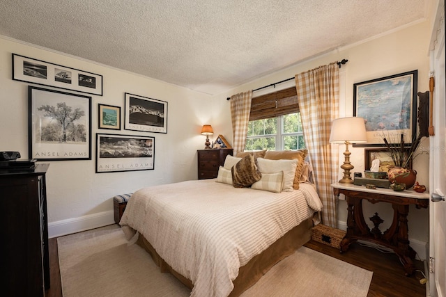 bedroom with a textured ceiling, baseboards, and wood finished floors