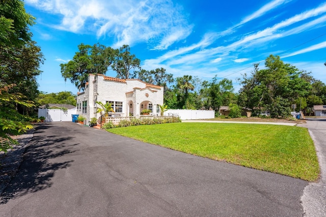 mediterranean / spanish-style house with a gate, stucco siding, fence, aphalt driveway, and a front yard