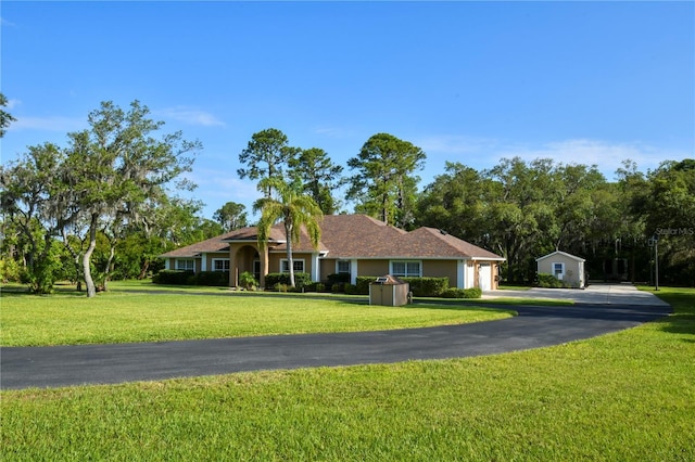 ranch-style home featuring a front lawn and stucco siding