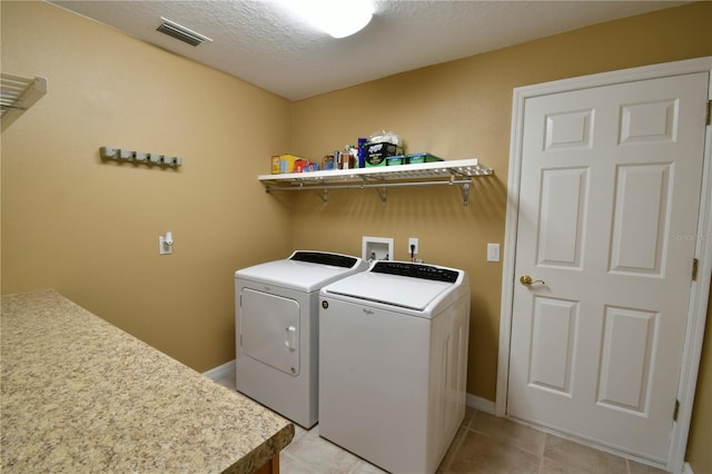 washroom with light tile patterned flooring, laundry area, baseboards, visible vents, and washing machine and dryer