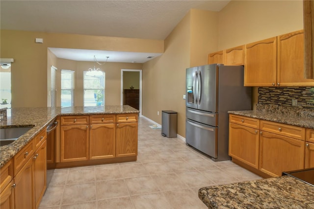 kitchen with brown cabinetry, pendant lighting, tasteful backsplash, dark stone counters, and stainless steel appliances