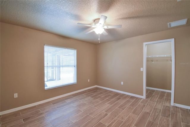 spare room with baseboards, ceiling fan, light wood finished floors, and a textured ceiling