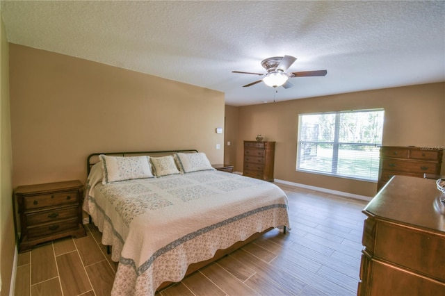 bedroom with baseboards, a ceiling fan, wood finish floors, and a textured ceiling