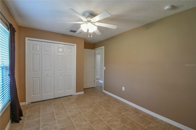 unfurnished bedroom featuring baseboards, visible vents, ceiling fan, and a closet