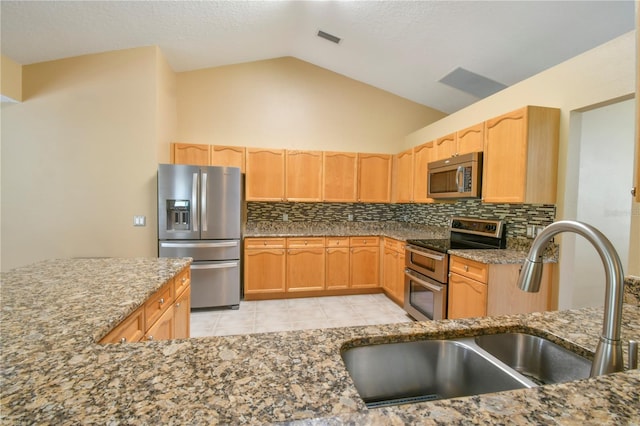 kitchen featuring visible vents, stone countertops, a sink, appliances with stainless steel finishes, and backsplash