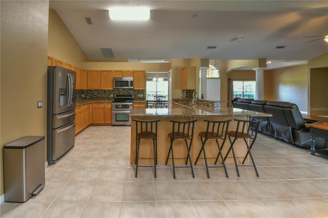 kitchen with decorative columns, open floor plan, backsplash, vaulted ceiling, and stainless steel appliances