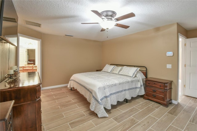 bedroom with visible vents, a textured ceiling, baseboards, and wood finish floors