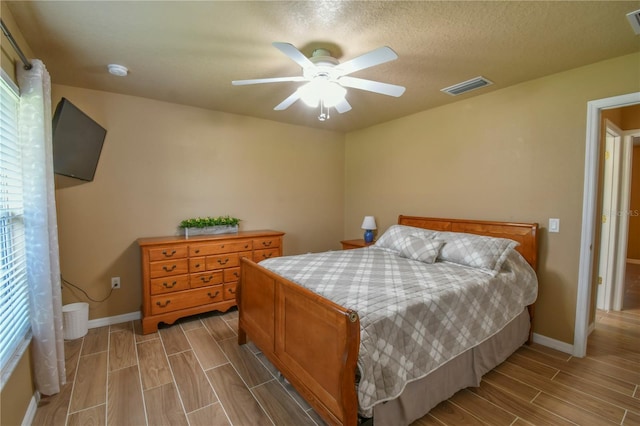 bedroom with visible vents, a ceiling fan, baseboards, and wood finish floors
