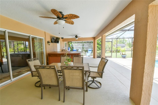 sunroom with outdoor dining area, a jacuzzi, and ceiling fan