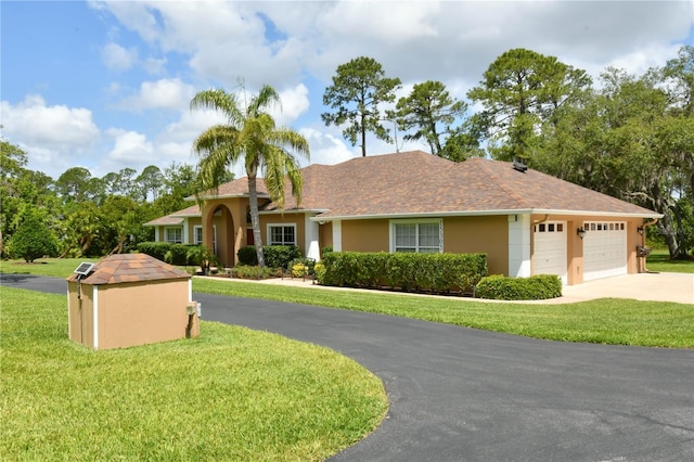 ranch-style home featuring stucco siding, an attached garage, driveway, and a front yard