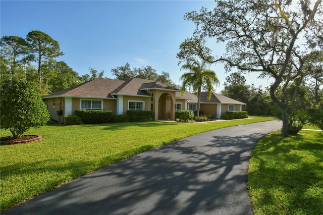 ranch-style home featuring stucco siding and a front lawn