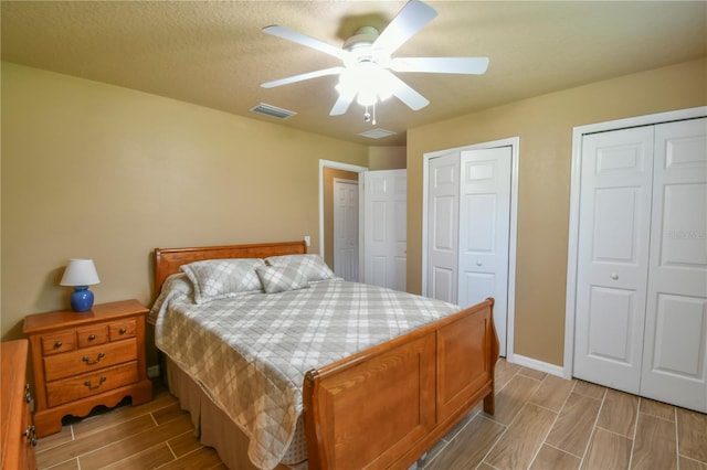 bedroom featuring ceiling fan, wood finish floors, two closets, baseboards, and visible vents