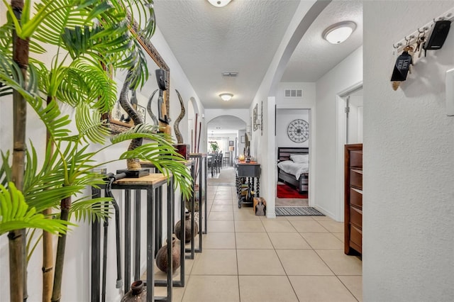 822 Sheen Cir, Haines City, FL 33844 - hall with visible vents, arched walkways, a textured ceiling, and light tile patterned floors